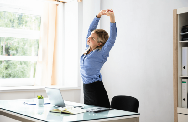 Person stretching arms above head while seated at a desk